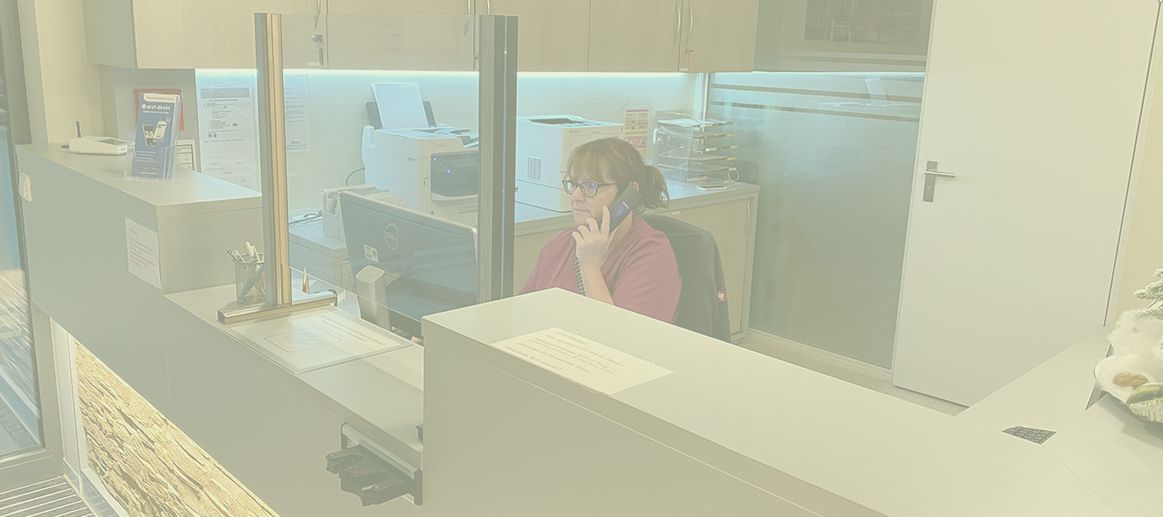 Sprechstundenhilfe hinter einer Praxistheke am Telefon.